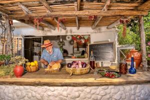 a man standing behind a counter with baskets of fruit at AKTI ARGO in Palaiokastro