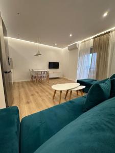 een woonkamer met een blauwe bank en een tafel bij Arkadia Saranda in Sarandë