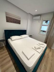 een slaapkamer met een bed met witte lakens en een raam bij Arkadia Saranda in Sarandë