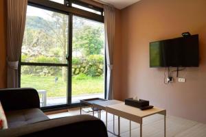 a living room with a couch and a tv on the wall at MTNY Hotel in Zhushan