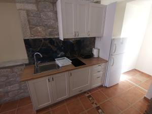 a kitchen with white cabinets and a sink and a refrigerator at Taletos Apartments in Stoupa