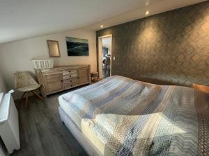 Schlafzimmer mit einem Kingsize-Bett und einer Kommode in der Unterkunft Krummes Häuschen in Großheide