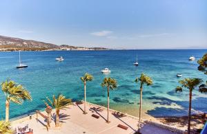 a view of a beach with palm trees and boats at Leonardo Royal Hotel Mallorca in Palmanova