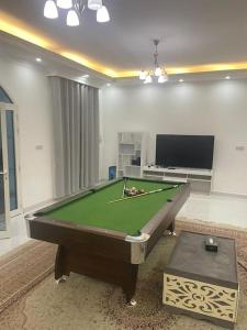a living room with a pool table and a tv at Al Fay Farmhouse in Sinādil