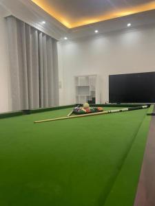 a room with a pool table with cues on it at Al Fay Farmhouse in Sinādil