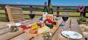 a wooden table with two glasses of wine and cheese at Sunny Bank- Countryside Escape with Private Hot Tub and countryside views in Carmarthen
