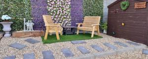 Deux chaises assises sur l'herbe dans une arrière-cour dans l'établissement Sunny Bank- Countryside Escape with Private Hot Tub and countryside views, à Carmarthen