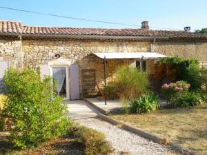 a stone house with an umbrella in a yard at AU MAS D'EMMA in Bourg-Saint-Andéol