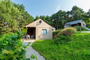 a small house with a porch in a yard at Camping de La Vernhe in Saint-Amans-des-Cots