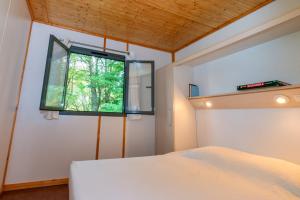 Schlafzimmer mit einem Bett und einem Fenster in der Unterkunft Camping de La Vernhe in Saint-Amans-des-Cots