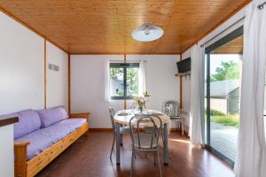a living room with a purple couch and a table at Camping de La Vernhe in Saint-Amans-des-Cots