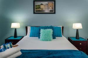 1 dormitorio con 1 cama con almohadas azules y 2 lámparas en McLaren Vale Studio Apartments, en McLaren Vale