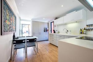 a kitchen with white cabinets and a table and chairs at Unique Villa -1 km to Beach, private Natural pool, Tennis Court & Jumping Mat in Sagres