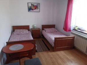 a bedroom with two beds and a table and a window at Pod Modrzewiem ul Modrzewiowa 7 in Milicz