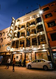 新德里的住宿－Hotel Baba Deluxe -By RCG Hotels，停在大楼前的白色汽车