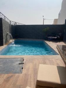 a swimming pool with blue water and a brick wall at Villa Aziza piscine privée in Oujda