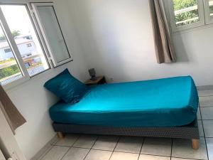 - un canapé bleu dans une pièce avec deux fenêtres dans l'établissement Villa les Poinsettias, à Saint-Pierre