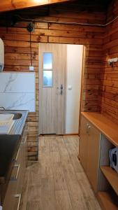 a kitchen with a door in a wooden wall at SŁONECZNIK domki letniskowe Charbrowo-Łeba in Charbrowo
