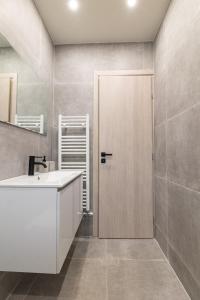 uma casa de banho com um lavatório e uma porta de madeira em Greyt Apartments Glyfada em Atenas