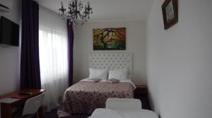 a small bedroom with a bed and a chandelier at Iris Boutique in Otopeni