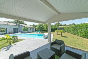 un patio con sillas y una piscina en Villa Blanca - Maison climatisée piscine privée, en Saint-Selve