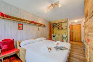 - une chambre avec un lit blanc et une chaise rouge dans l'établissement Studio Abete Rosso 500m From Ski - Happy Rentals, à Sauze dʼOulx