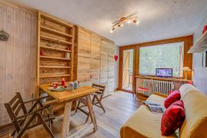 sala de estar con pared de madera, mesa y sillas en Studio Abete Rosso 500m From Ski - Happy Rentals en Sauze dʼOulx