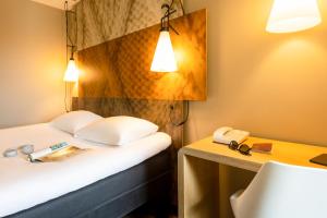 a hotel room with a bed and a desk with a phone at ibis Leuven Centrum in Leuven