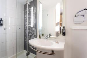 uma casa de banho com um lavatório e um chuveiro com um espelho. em ibis Leuven Centrum em Lovaina