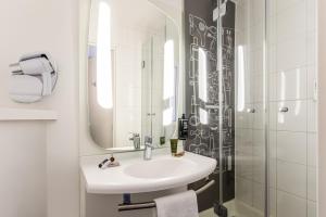 ein Bad mit einem Waschbecken und einer Dusche mit einem Spiegel in der Unterkunft ibis Leuven Centrum in Löwen