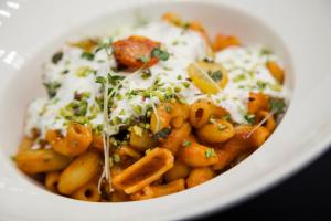 un piatto bianco di cibo con pasta e formaggio di Freina Mountain Lifestyle Hotel a Selva di Val Gardena