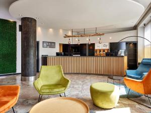 eine Lobby mit Stühlen, Tischen und einer Bar in der Unterkunft Mercure Hotel Düsseldorf City Center in Düsseldorf