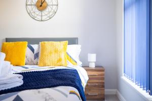 - une chambre avec un lit doté d'oreillers jaunes et bleus dans l'établissement Studios with Ensuite Showers & Share Kitchens Prime Location near Hospital, Town Center Apt 3, à St Helens