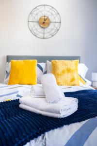 1 cama con toallas y reloj en la pared en Studios with Ensuite Showers & Share Kitchens Prime Location near Hospital, Town Center Apt 3 en Saint Helens