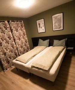a large bed in a bedroom with two pictures on the wall at Korshamn Rorbuer in Lyngdal