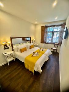 a bedroom with a large bed with a yellow blanket at CLAREN´S BOUTIQUE ROOMS in Cangas del Narcea