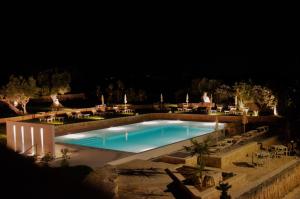 una piscina por la noche con mesas y sillas en Masseria Torrepietra, en Monopoli