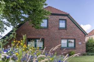 a brick house with windows and a field of flowers at 50043... in Carolinensiel