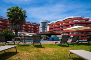 un groupe de chaises et de parasols devant un bâtiment dans l'établissement MS Aparthotel, à Linda-a-Velha