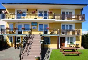 a yellow building with balconies and a picnic table at Pokoje Gościnne Heland in Jastrzębia Góra