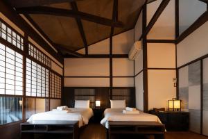 two beds in a room with large windows at KyoMachiya Stars in Kyoto