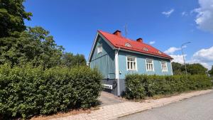 una casa azul con techo rojo en una calle en Tunnelmallinen puutalohuoneisto. en Turku