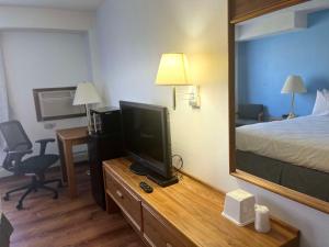 a hotel room with a tv and a bed and a mirror at SureStay by Best Western Glendive Yellowstone River in Glendive