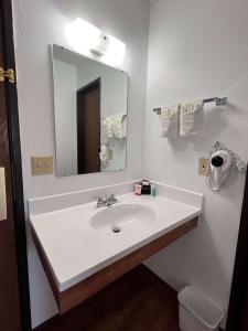 La salle de bains est pourvue d'un lavabo blanc et d'un miroir. dans l'établissement SureStay by Best Western Glendive Yellowstone River, à Glendive