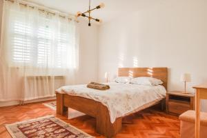 a bedroom with a bed with white sheets and a window at Apartman Platan in Metković