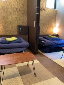 a room with two beds and a table in it at Hostel LodgingTokyo Minowa in Tokyo