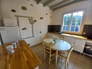 uma cozinha com uma mesa, uma mesa e um frigorífico em Maison de vacances em Adé