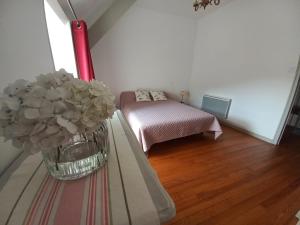 una habitación con una cama y un jarrón de flores sobre una mesa en Maison de vacances en Adé