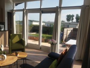 een woonkamer met een bank en een groot raam bij Vakantie Huisje nabij Leeuwarden en Friese kust in Dronrijp