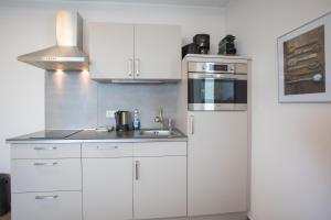 een keuken met witte kasten, een wastafel en een koelkast bij Appartement Brink Fichtenweg 26 in Winterberg +3 foto's